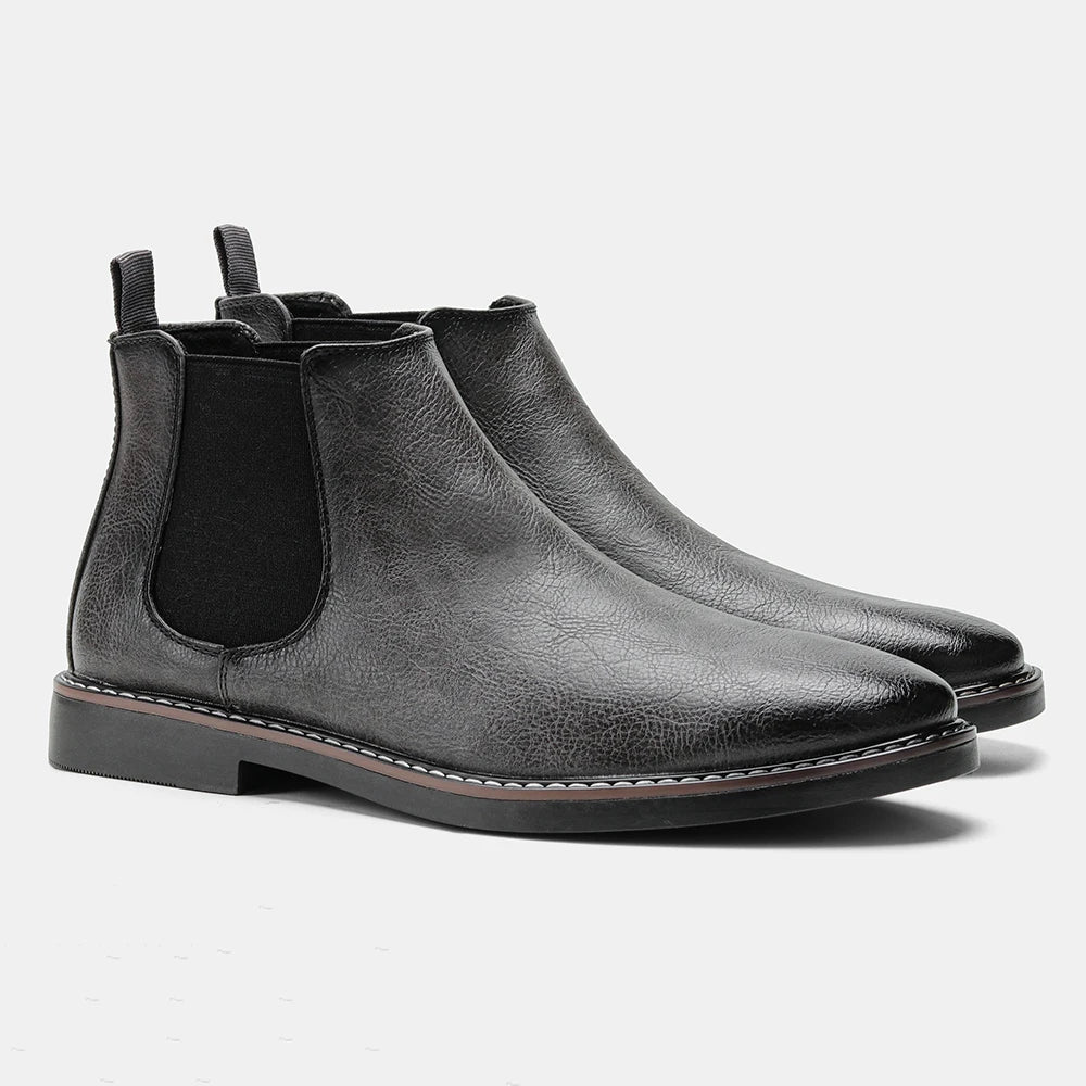 A pair of brown premium leather Chelsea boots with a black rubber sole, displayed in a way that shows the side profile and the boot's interior.