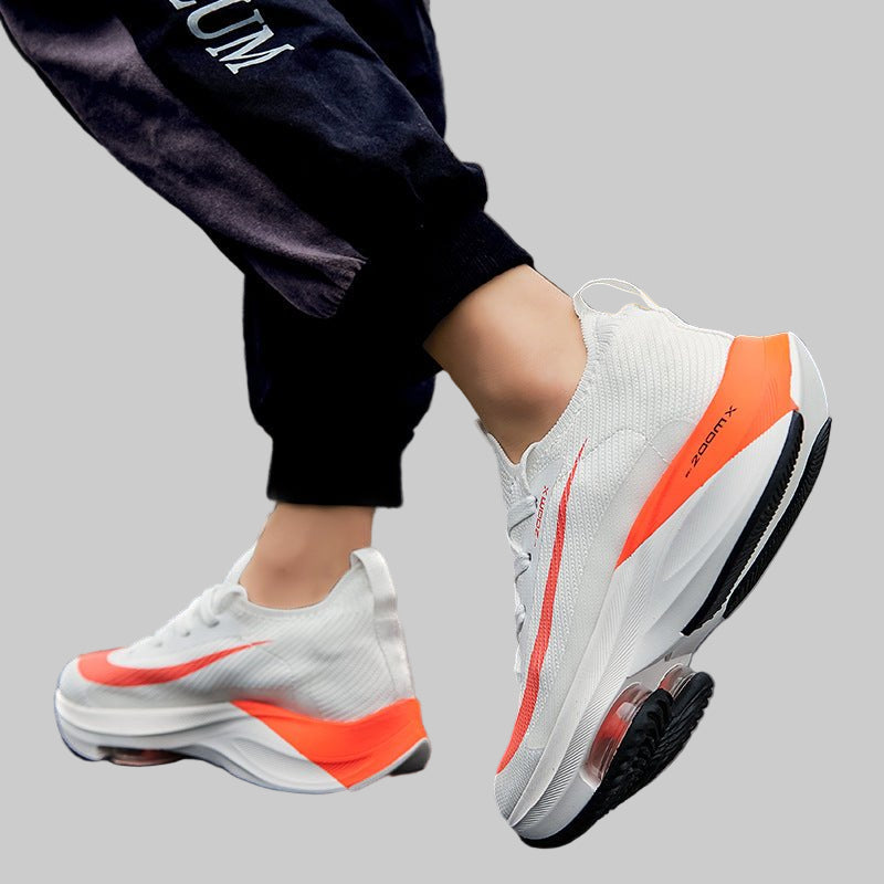 White sneakers with orange accents worn outdoors on a city street.