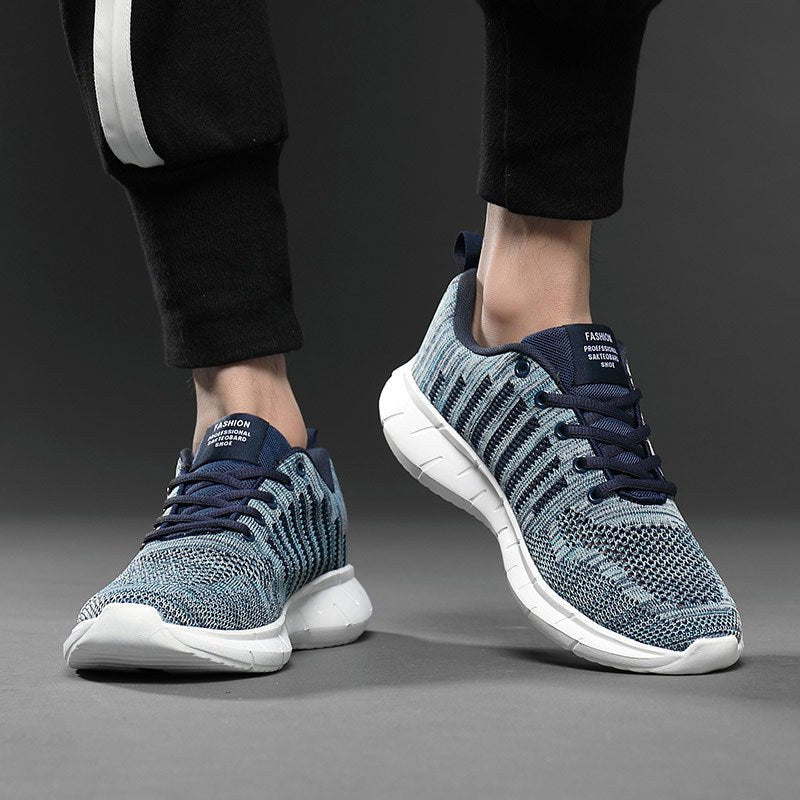 Blue and white sneakers worn with black pants on a gray background