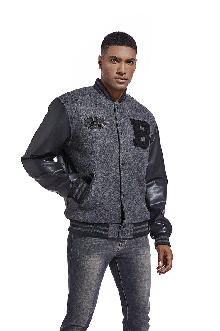 Man wearing a gray varsity jacket with black leather sleeves on a white background