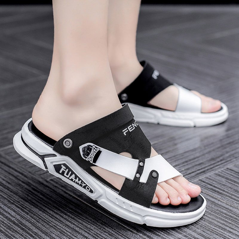Black and white sandals with brand logo on a gray floor