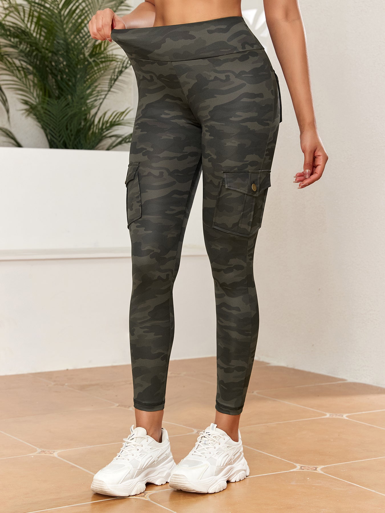 Person wearing camouflage cargo leggings with a neutral background