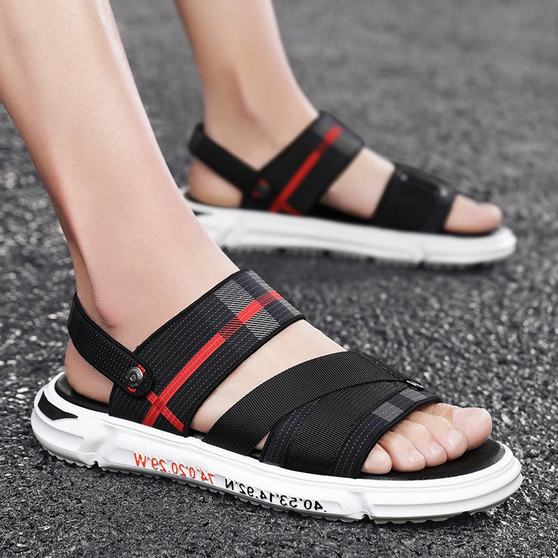 Black sandals with red accents worn on a dark surface