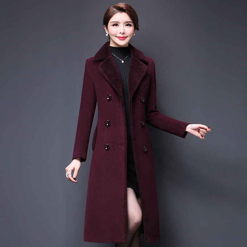 Woman wearing a long burgundy coat against a gray background