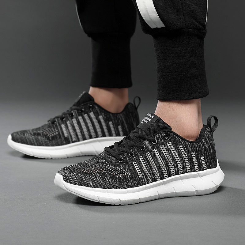 Black and white sneakers worn with black pants on a gray background