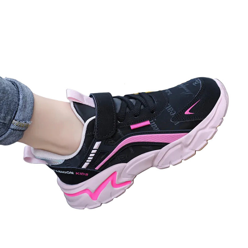 Black and pink sneaker worn by a child on a yellow railing.