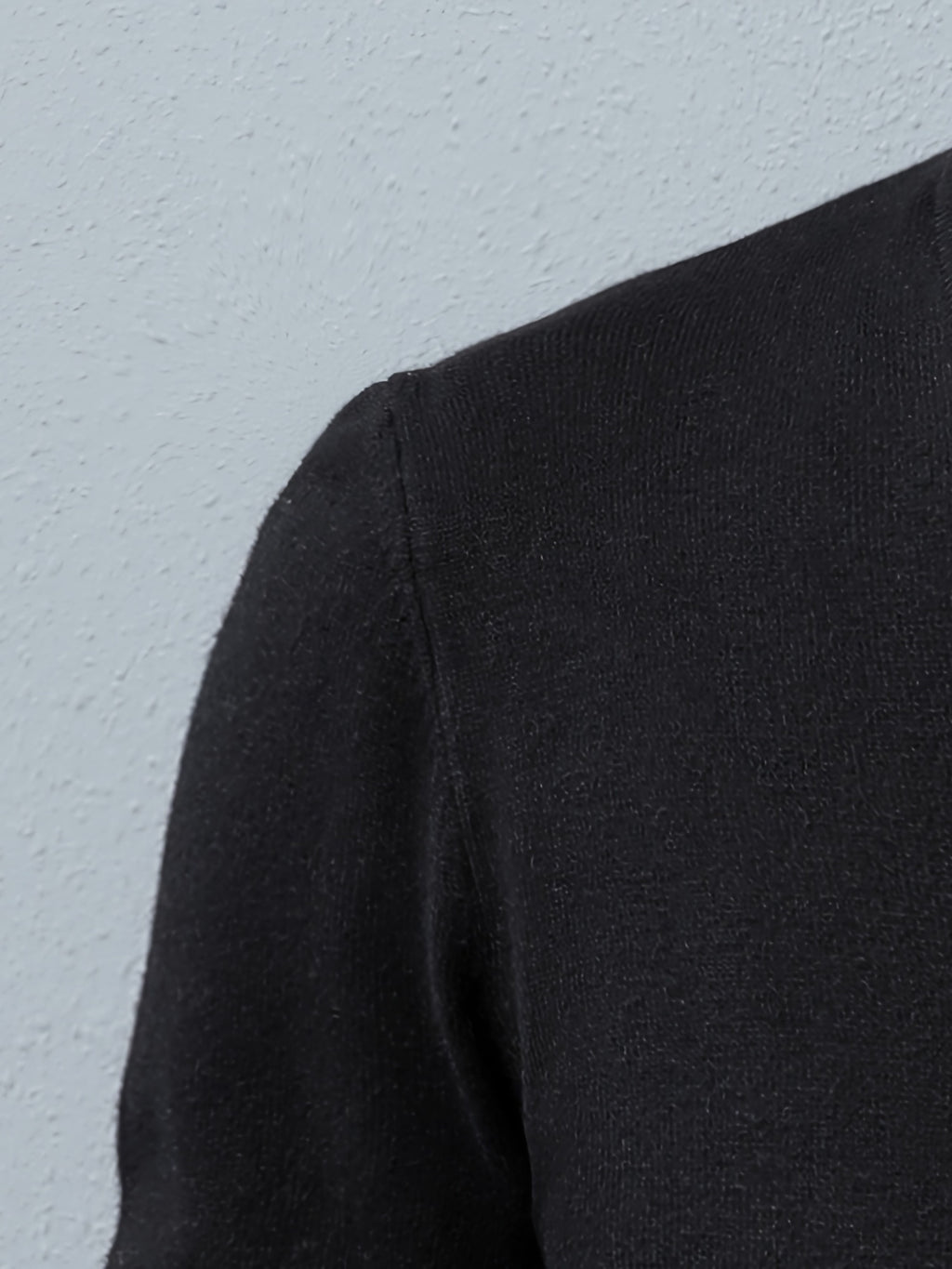 Close-up of a black sleeve against a light blue background