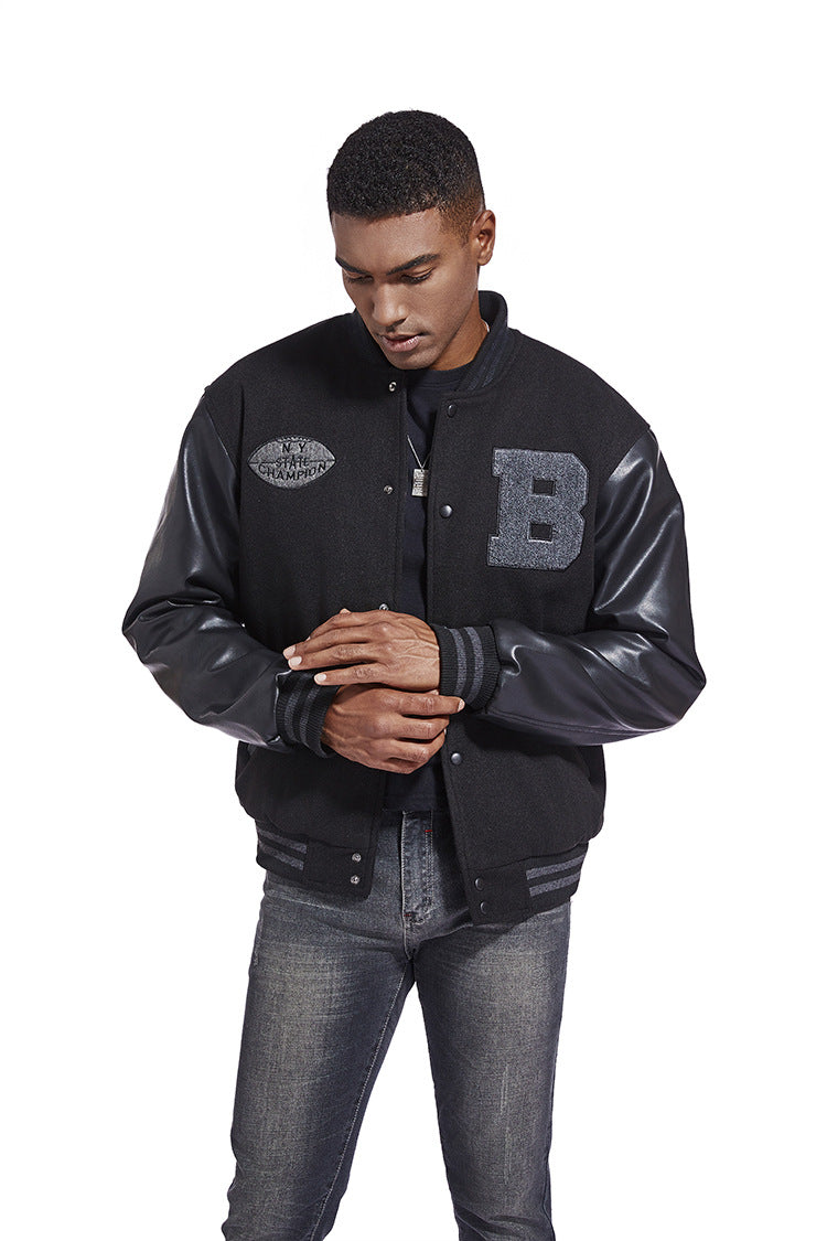 Man wearing a black varsity jacket with letterman design on a white background