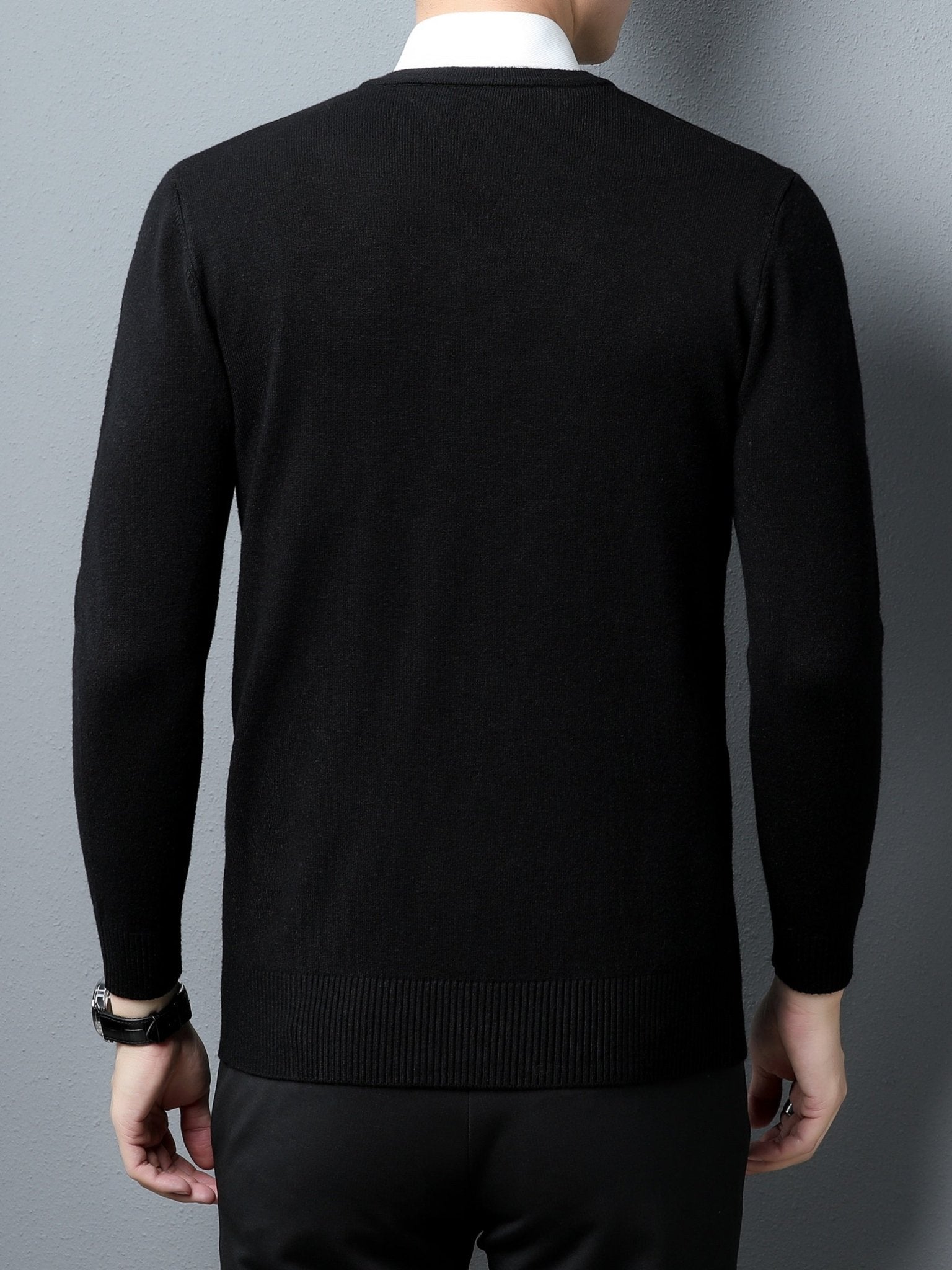 Person wearing a black Men's Knitted V-neck Sweater against a gray background