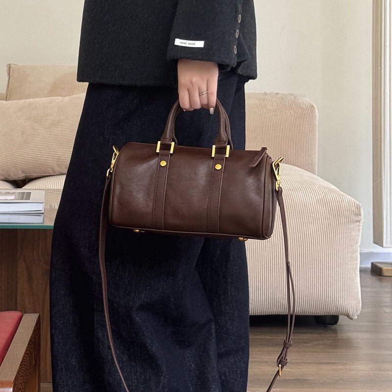 Person holding a brown leather handbag in a living room.