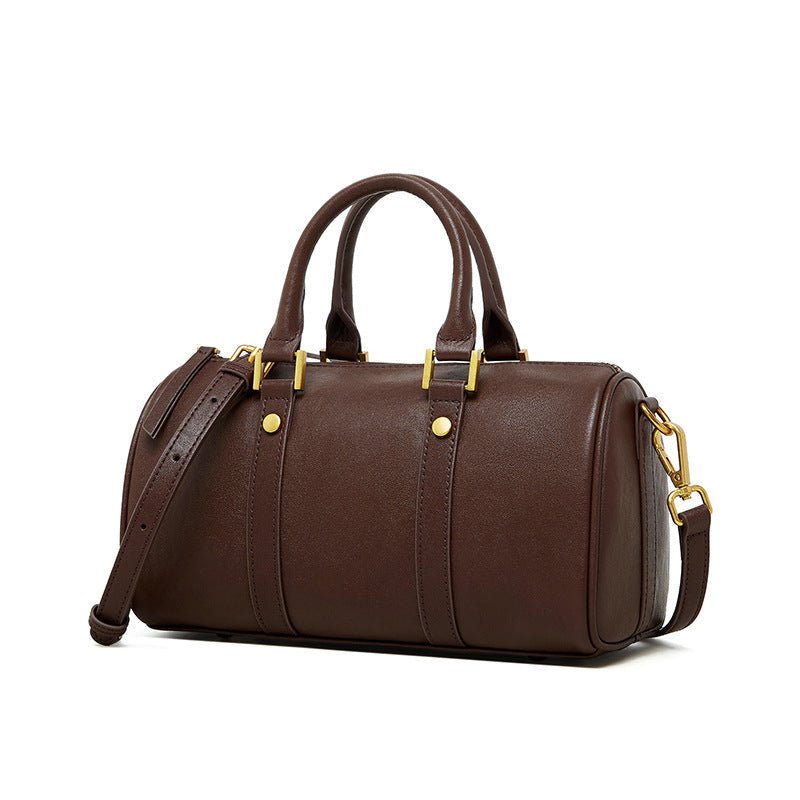 A person holding a brown retro portable cowhide crossbody bag with a leather texture and metal buckles.