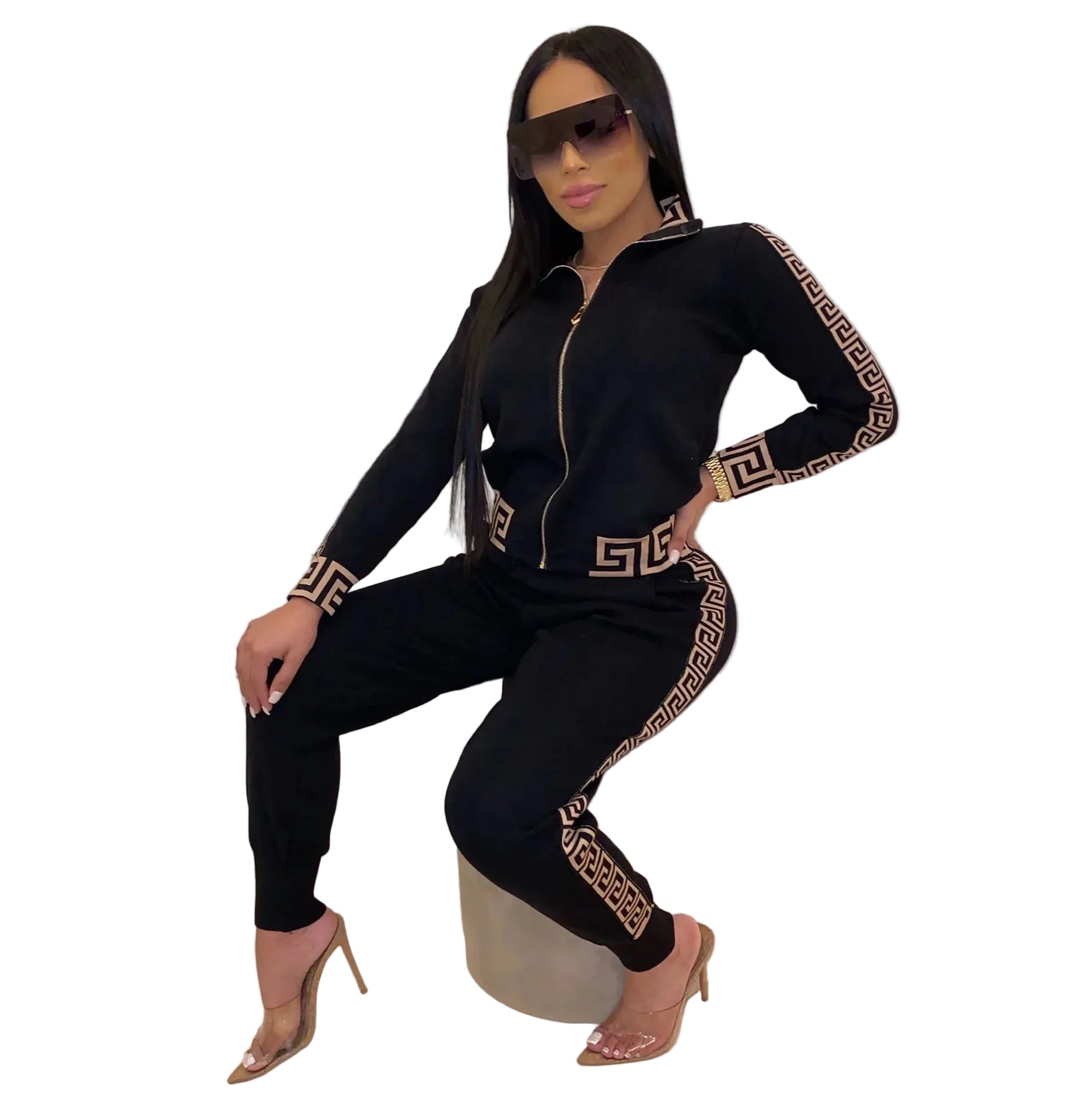 Women’s Zip-Up Tracksuit Set outfit with gold patterns sitting on a white stool against a white wall.
