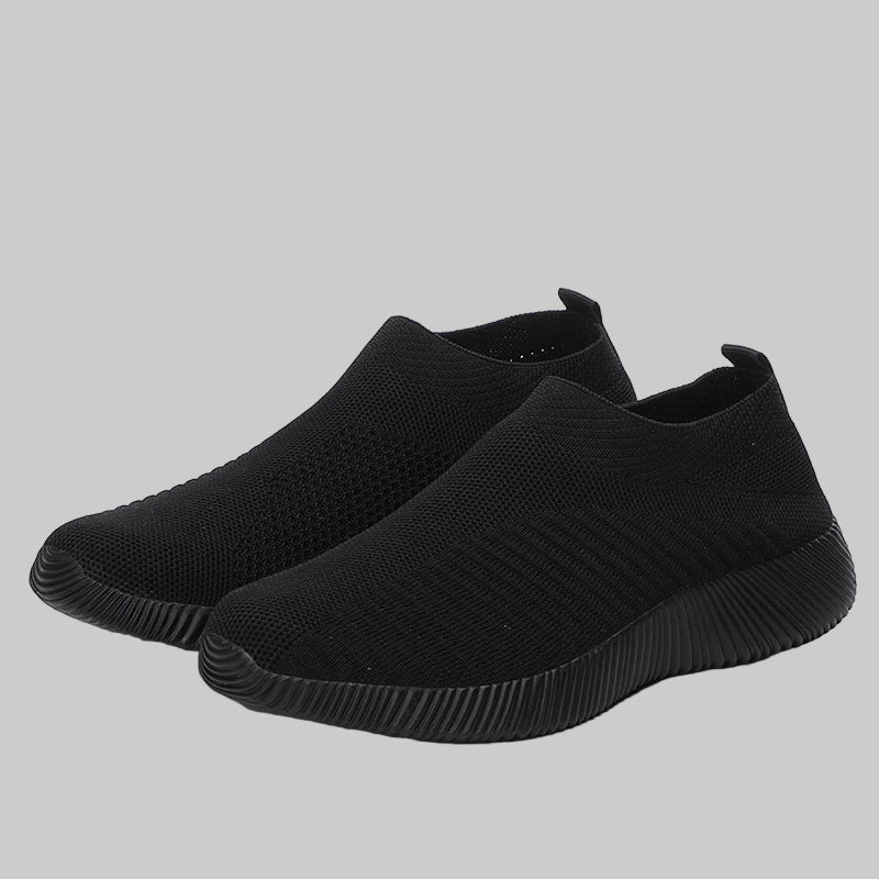 Pair of black slip-on sneakers on a white background