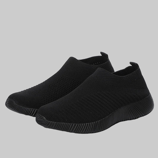 Pair of black slip-on sneakers on a white background