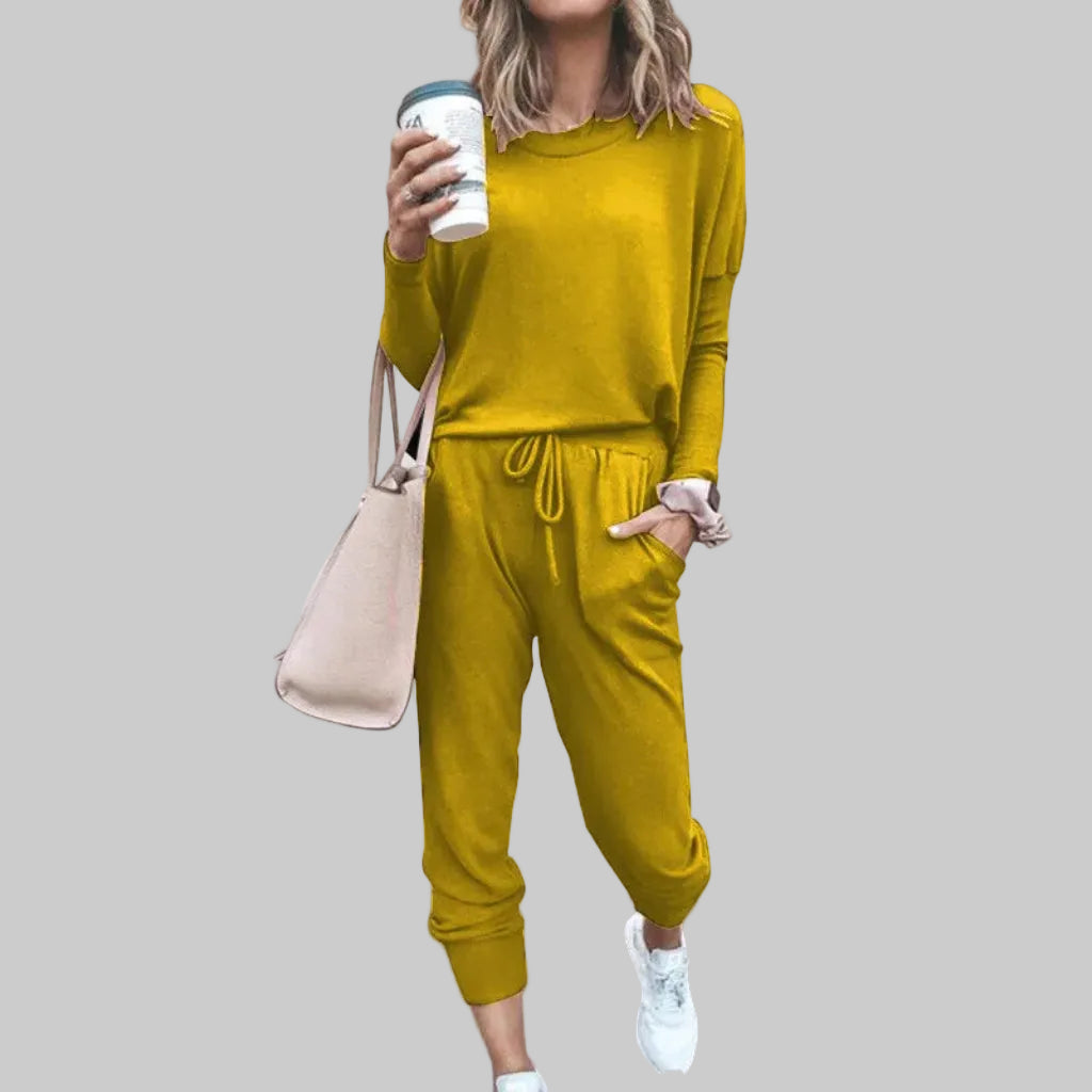Person wearing a mustard yellow outfit holding a coffee cup against a plain background