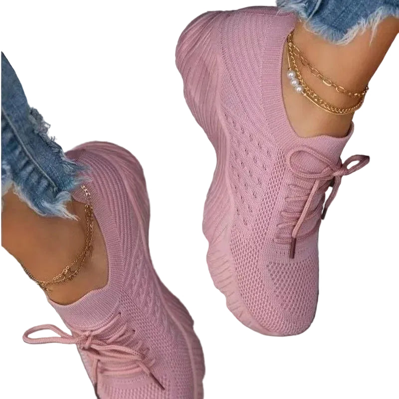 Women's Pink mesh sneakers with matching laces and textured soles, worn with distressed blue jeans.