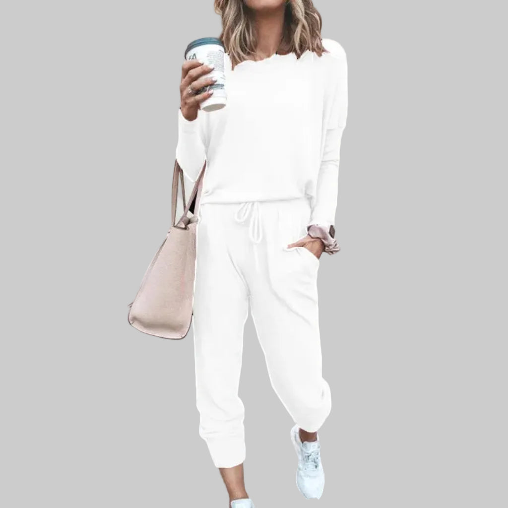 Person wearing a white outfit holding a coffee cup against a plain background
