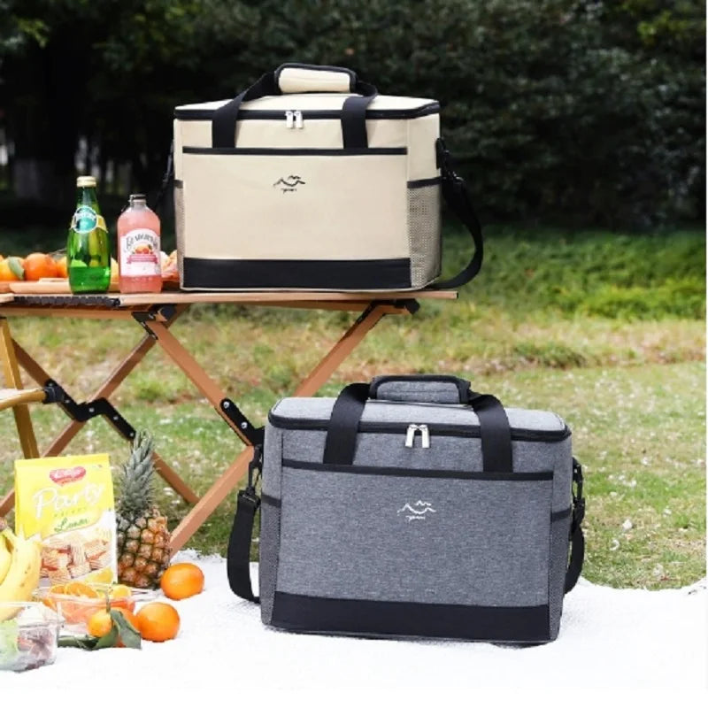 Two cooler bags on a picnic setup with fruits and drinks outdoors.