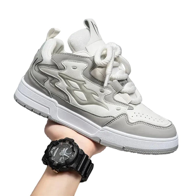 Gray and white sneaker held by a hand wearing a black watch on a gray background