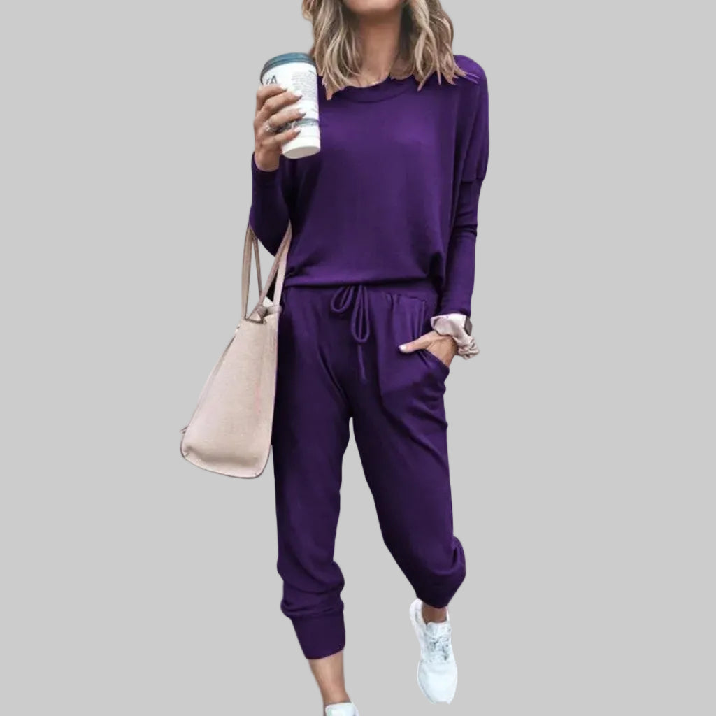 Person wearing a purple outfit holding a coffee cup against a plain background