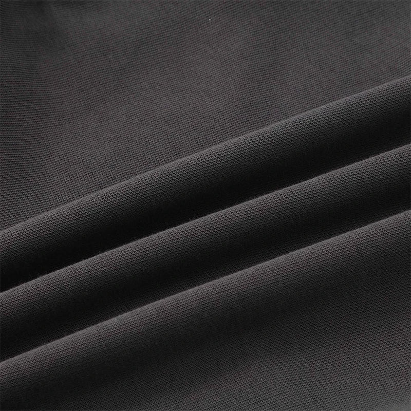 A close-up of dark charcoal gray or black textured fabric with soft diagonal folds showing the woven material detail.