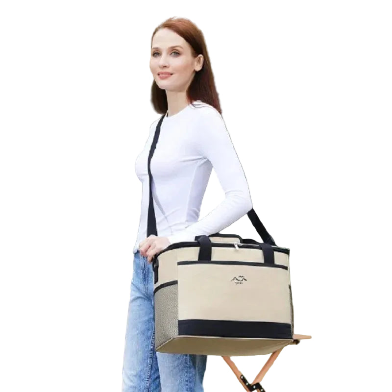 Woman holding a beige and black bag outdoors with greenery in the background