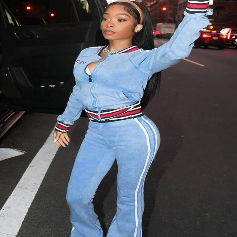 Person wearing a blue tracksuit with red and white accents on a street.