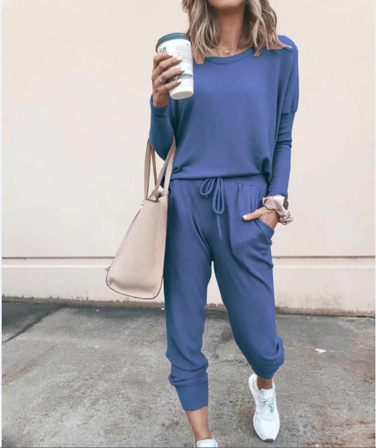 Person wearing a blue outfit holding a coffee cup against a beige wall.