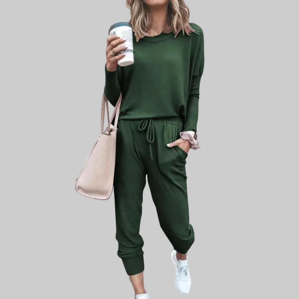Person wearing a green outfit holding a coffee cup against a plain background