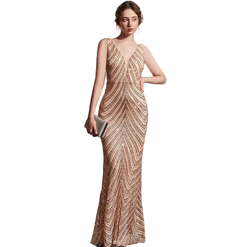 Woman in a patterned evening gown standing against a white wall.