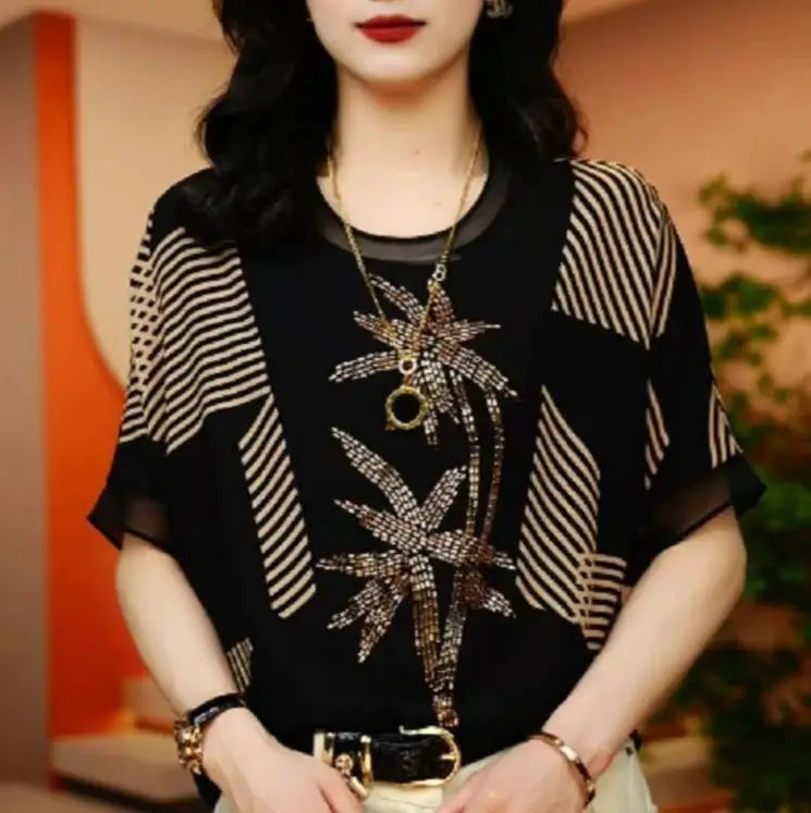 Woman wearing a black and white patterned top with a decorative necklace indoors.