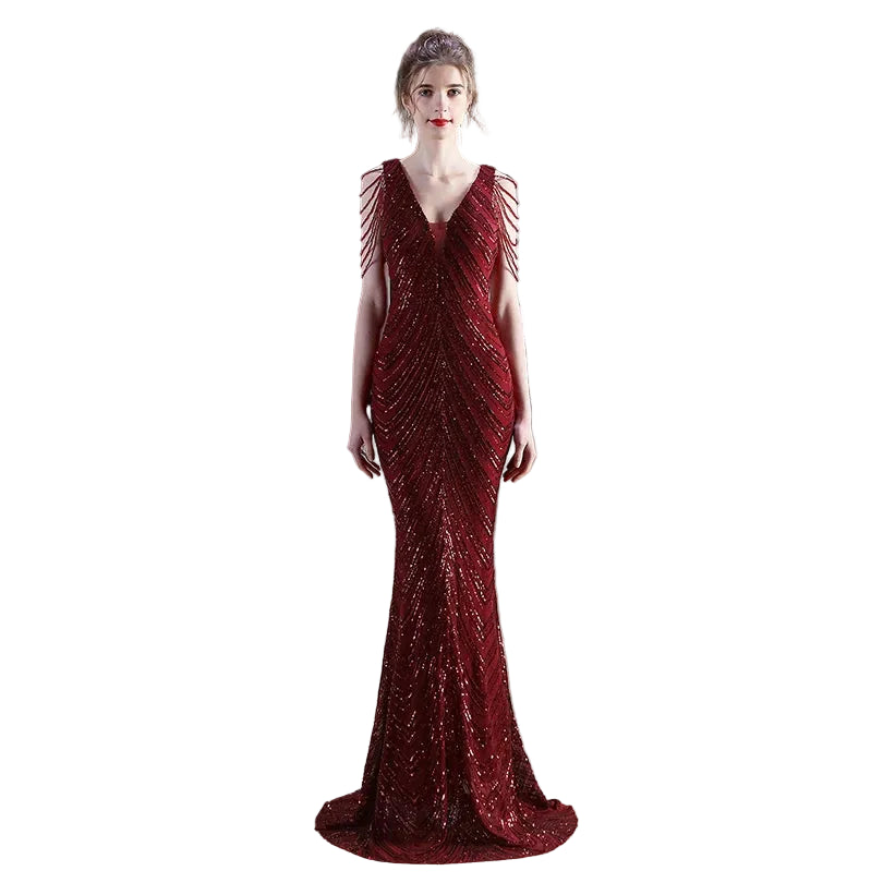 Woman in a red beaded evening gown standing in an indoor setting with decor elements.