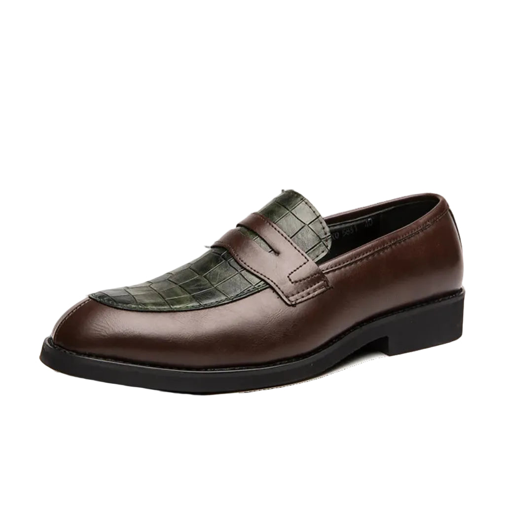 A man's foot wearing a brown crocodile-patterned leather shoe with a buckle strap, alongside a wooden floor and a wristwatch.