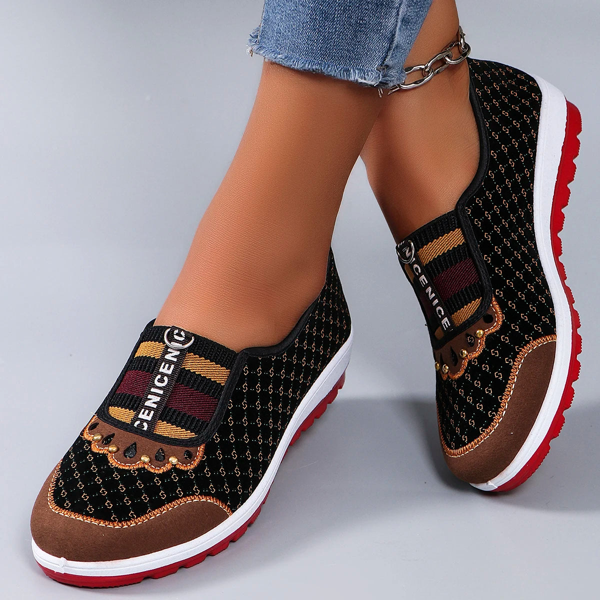 Black and brown patterned shoes with red soles on a gray background