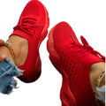 Women's red mesh sneakers with matching laces and textured soles, worn with distressed blue jeans.