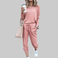 Person wearing a pink tracksuit holding a coffee cup against a plain background