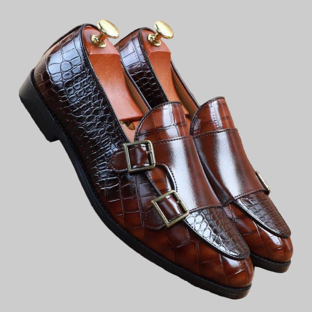 Brown leather shoes with gold buckles on a gray background
