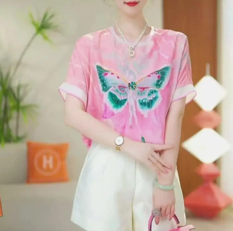 Person wearing a pink shirt with a butterfly design in a casual setting