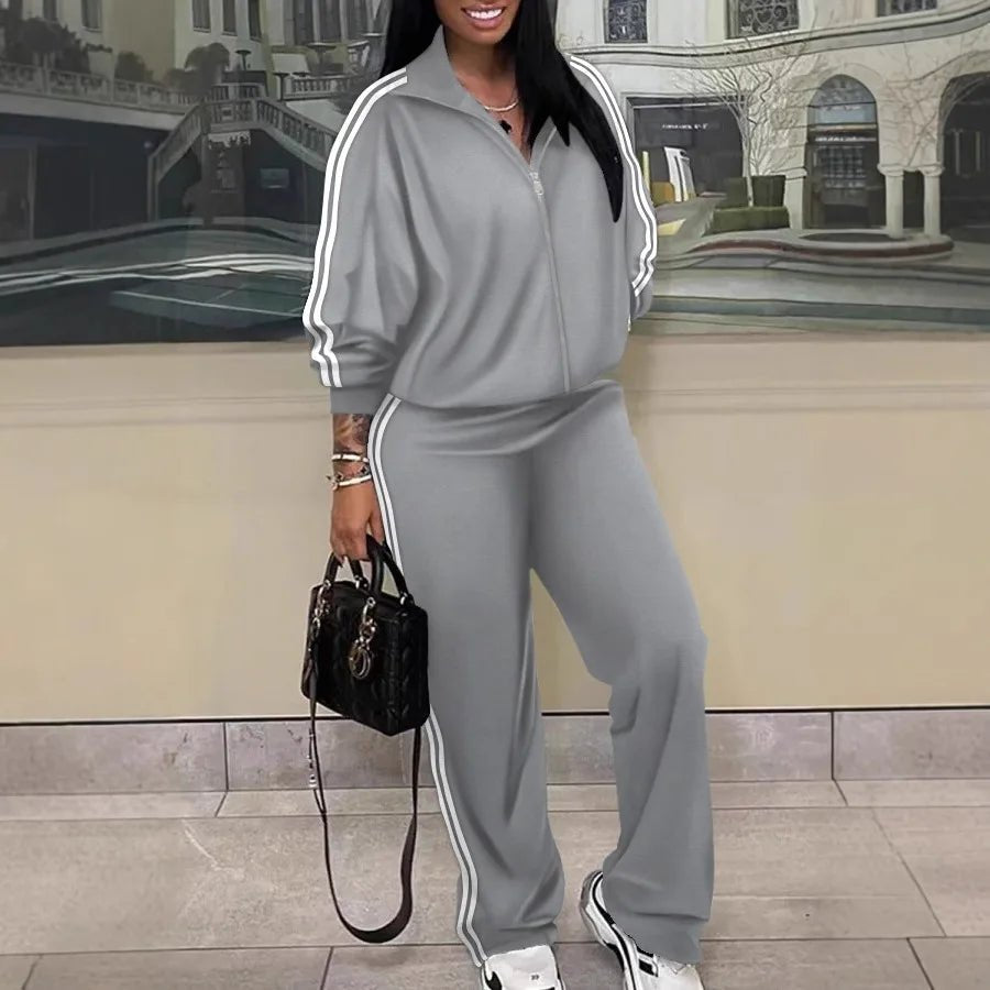 Person wearing a gray tracksuit with white stripes in an urban setting.