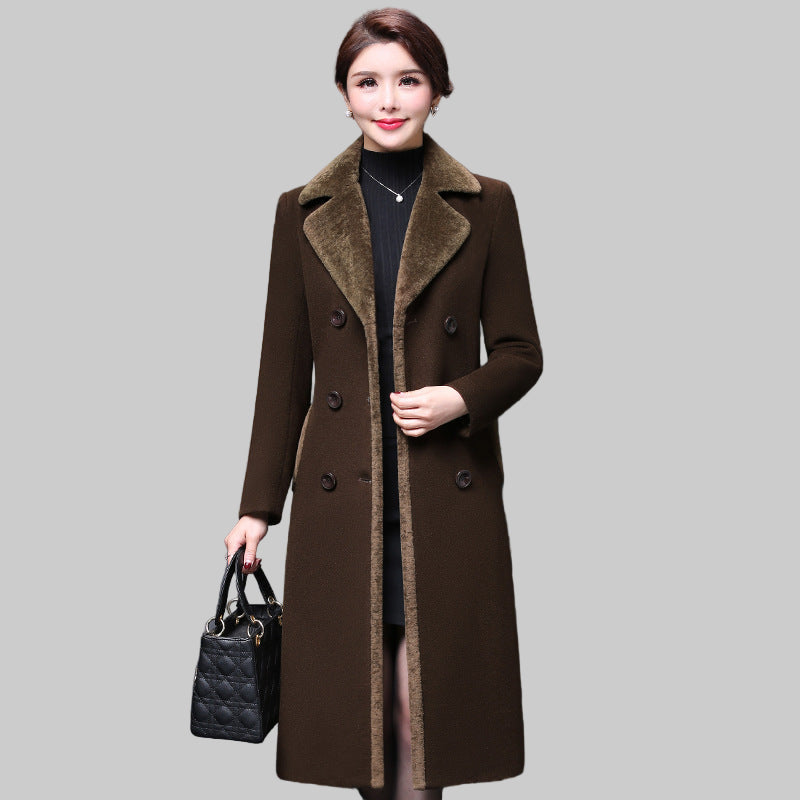 Woman wearing a brown coat holding a black handbag against a gray background
