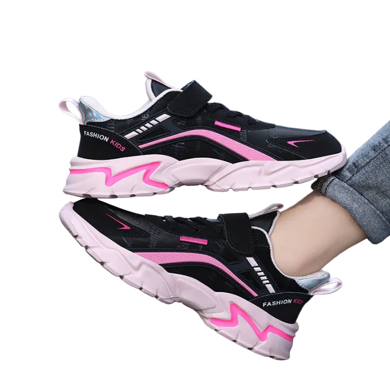 Black and pink children's sneakers on a blurred street background
