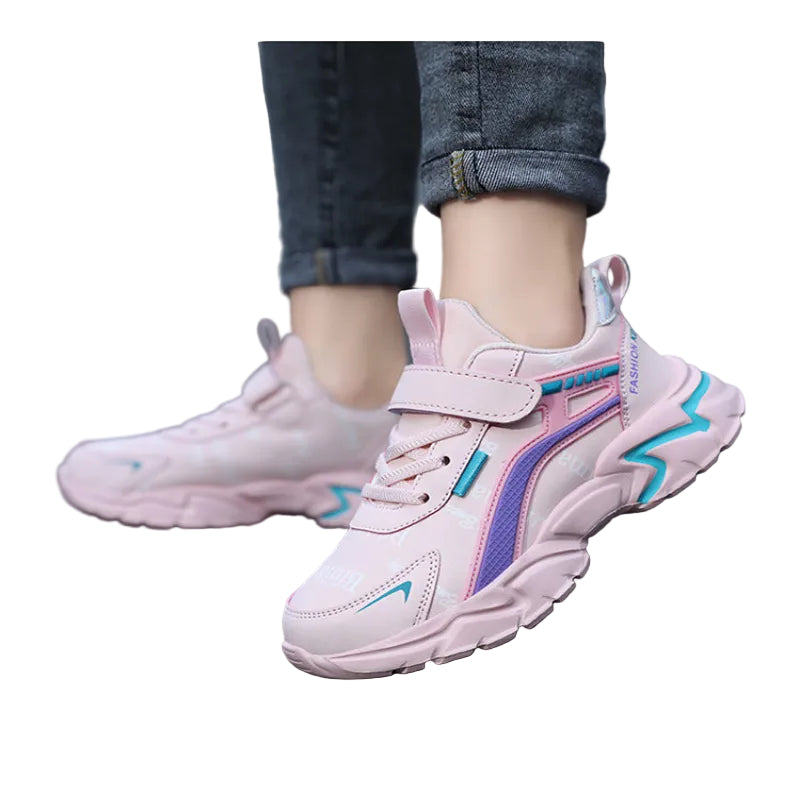 Pink children's sneakers with blue accents worn on a blurred street background