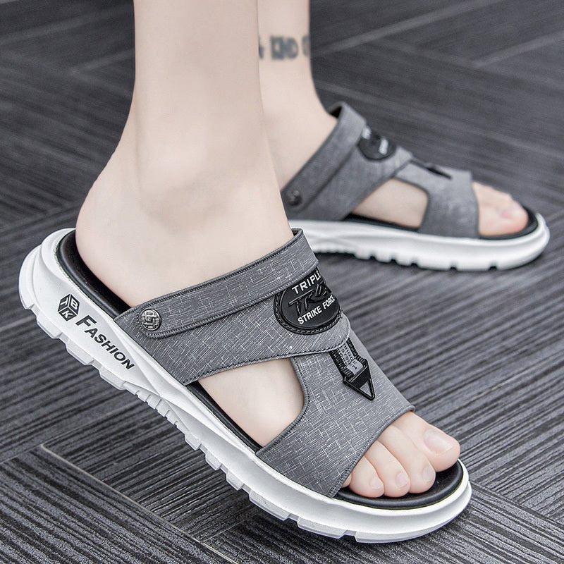 Gray sandals with white soles worn by a person on a wooden floor.