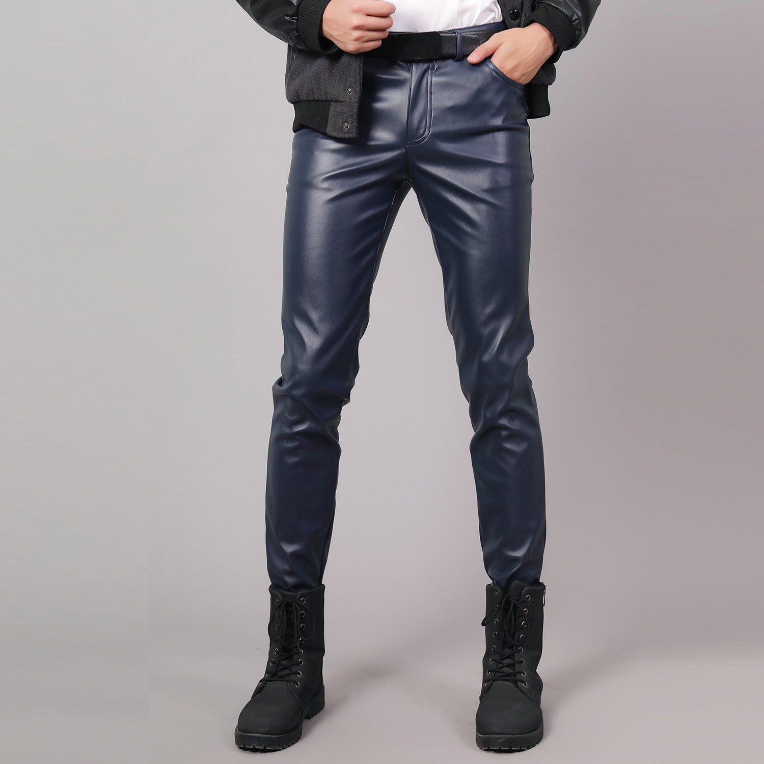 Person wearing blue leather pants and black boots on a gray background