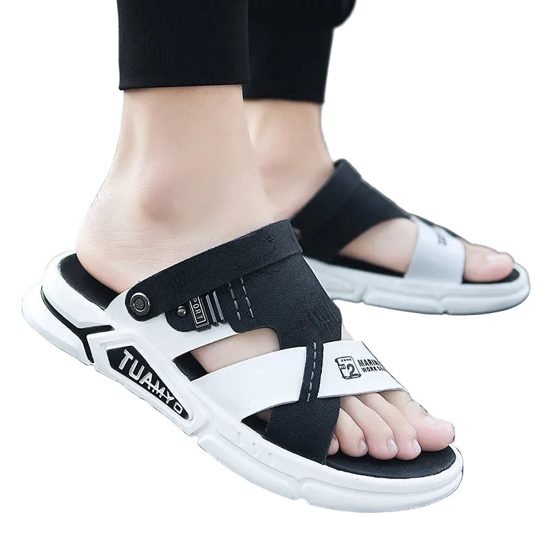 Black and white sandals worn on feet standing on a gray surface