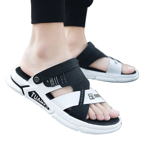 Black and white sandals worn on feet standing on a gray surface