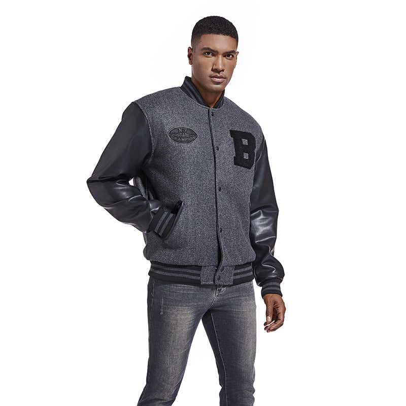 Man wearing a gray varsity jacket with black leather sleeves on a white background