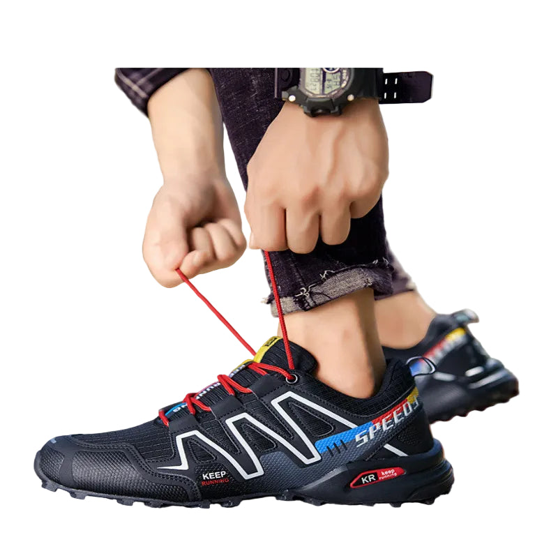 Person tying the laces of black hiking shoes with red accents on a natural background